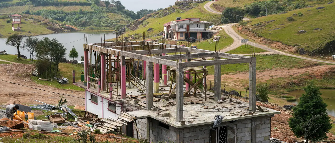 A residential building under construction on a hillside, with columns and slabs in place