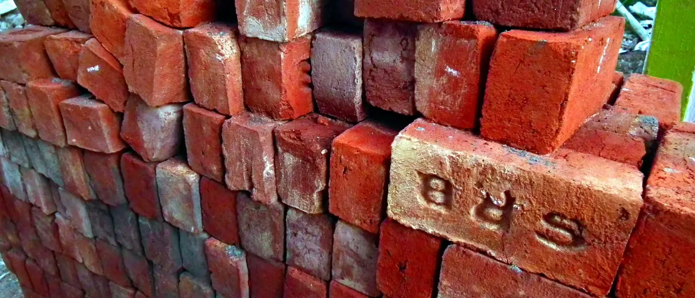 A stack of red clay bricks used for building work in India