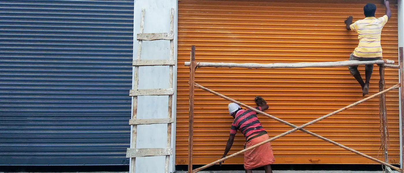 Workers painting the outside wall of a house in a village